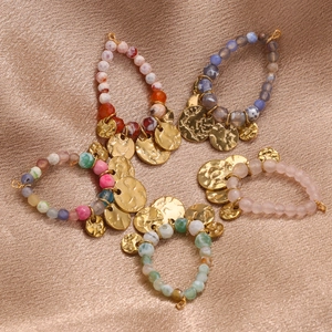 Handmade bohemian beaded bracelets with gold charms on champagne satin background