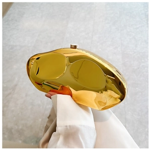 Close-up of golden pebble-shaped evening clutch bag with mirrored metallic finish