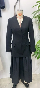 Detail of a chic black two-piece skirt suit set with V-neck blazer and pleated mini skirt
