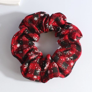 Close-up of red and black plaid plush scrunchie with festive white snowflake patterns