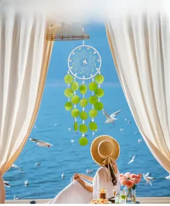 Detail of handmade woven dreamcatcher hanging with green translucent discs and moon pendant