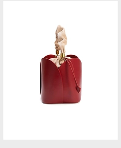 Detailed view of red petal-shaped bucket bag with gold rings and beige drawstring liner