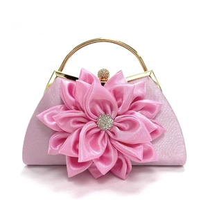 Detalle de bolso de satén rosa con flor grande de tela y centro de diamantes de imitación