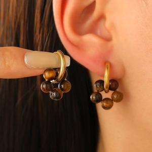 Elegant gold hoop earrings with brown beaded flower charms shown on ear and hand