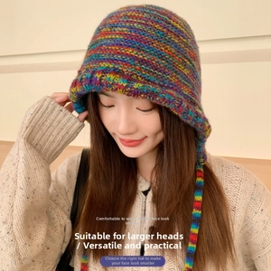 Close-up of fluffy rainbow knit earflap hat with long braided ties and soft texture
