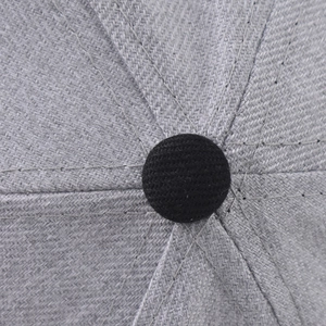 Detailed macro view of the grey twill cotton crown and black top button on the baseball cap