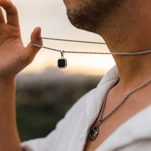 Collana da uomo a fune d'argento con pendente geometrico nero quadrato alla luce del sole