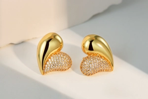 Detailed view of asymmetrical gold heart earrings with half-polished and half-pave zircon