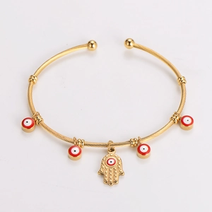 Detail of gold twisted open bangle with red evil eye beads and Hamsa hand charm