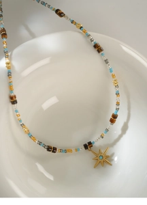 Detailed view of beaded star necklace with tiger eye stones on white ceramic bowl