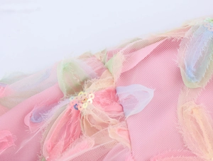 Detailed macro shot of pink mesh fabric featuring colorful sequins and fringe textures