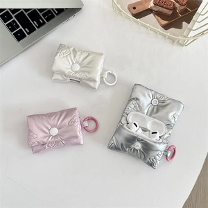 Macro detail of quilted AirPods cases with embossed bows and metallic hooks