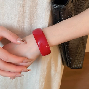 Détail d'un bracelet en acrylique rouge avec motif marbré et surface polie miroir