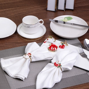 Detail view of colorful Christmas napkin rings featuring reindeer and Santa on white linen