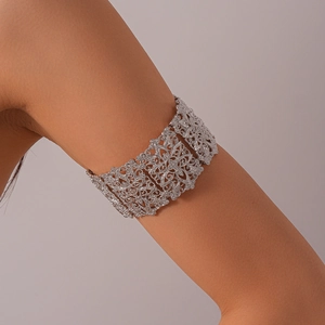Détail d'un large bracelet de bras argenté avec des motifs floraux évidés et des cristaux