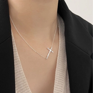 Detail of 925 sterling silver cross necklace worn by model with professional styling