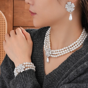 Model wearing a three-layer pearl necklace set with rhinestone flowers and drop pendants