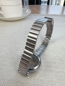 Macro view of stainless steel watch back and silver chain strap on a textured surface