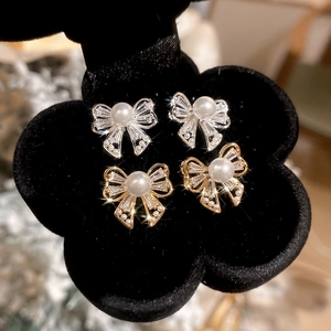Detailed macro view of bow earrings featuring faux pearls and sparkling zircons