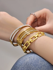 Detail von gestapelten 18k vergoldeten Armbändern mit Zirkonia und Kettenglied-Design