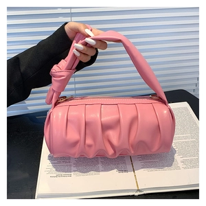 Close-up of pink ruched cloud bag with knotted handle detail and golden zipper