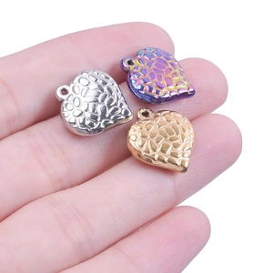 Macro view of small heart charms in gold, silver and rainbow finish with hammered texture