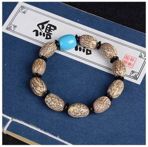 Makroansicht von Bodhi-Samen-Armband mit blauer Perle auf traditionellem Buch