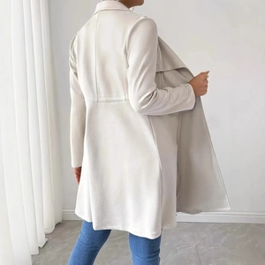 Detail view of the back tailoring of a stylish beige long-sleeved trench coat for women