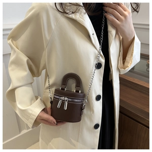 Sac cylindre vintage marron porté avec un trench-coat beige pour un look chic