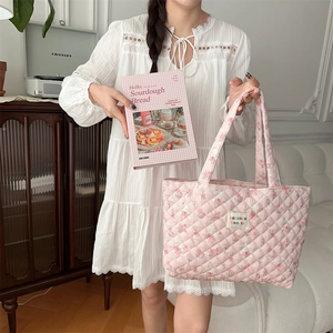 Detail of pink floral quilted tote bag carried by model in a soft home setting