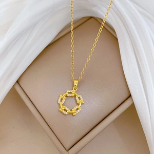 Detailed view of a gold circular link pendant necklace with cubic zirconia in a jewelry box