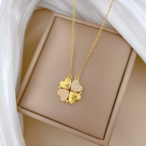 Close-up of golden clover pendant with crystal inlay on a beige jewelry gift box