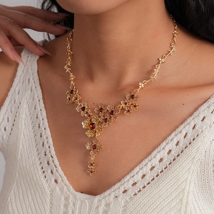 Detail of vintage gold flower necklace with red and amber crystals on model's neck