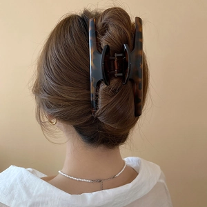 Detail showing a large tortoiseshell hair claw clip securing a chic bun on a female model