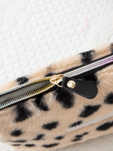 Detail of silver zipper and black leather puller on leopard print plush cosmetic bag