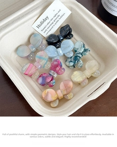 Detail of acetate butterfly hair clips with rhinestones and marble texture on a tray