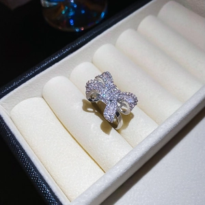 Macro detail of silver bow ring with shimmering white zircon stones on velvet display