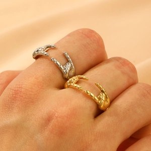 Macro shot of gold and silver gesture-shaped open rings on soft silk fabric background