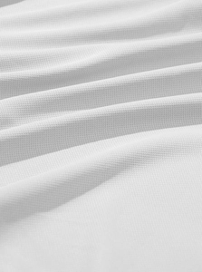 Macro view of white pique knit fabric texture and breathable mesh pattern for polo shirt