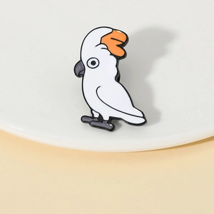 Détail de la broche perroquet en émail avec finition glacée blanche et orange