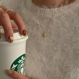 Minimalist gold ball pendant necklace and matching ring on a soft white sweater