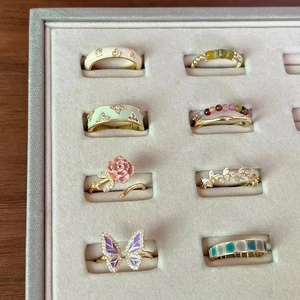 Set of colorful enamel butterfly and floral adjustable gold rings in a jewelry tray