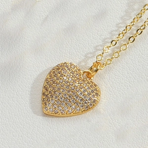 Detailed close-up of a gold heart pendant necklace encrusted with shimmering cubic zirconia
