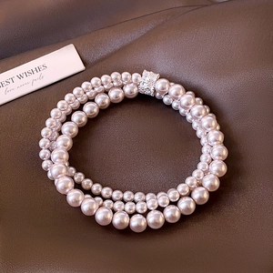 Elegant multi-layer pearl bracelet with zircon cylinder clasp on textured dark background