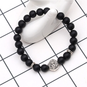 Close-up of black matte lava stone beaded bracelet with silver lion head charm on hand model