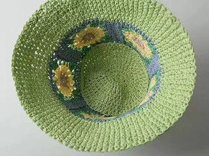 Close-up of handmade crochet straw hat with green texture and yellow sunflower details