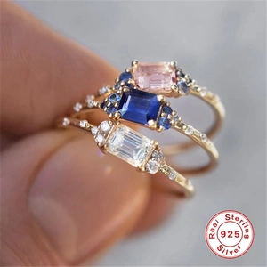 Macro shot of 925 silver rings with colorful rectangular zircon gemstones in gold finish