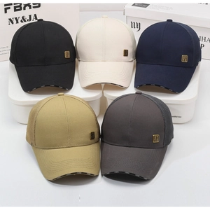 Detail of five assorted breathable mesh trucker hats in neutral tones on white stand