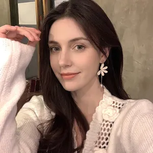 Elegante asymmetrische lange Blütenohrringe mit weißen Blumen und Perlen am Modell