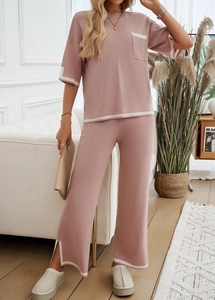 Détail d'un ensemble en maille rose avec liserés blancs et pantalon fendu sur le côté